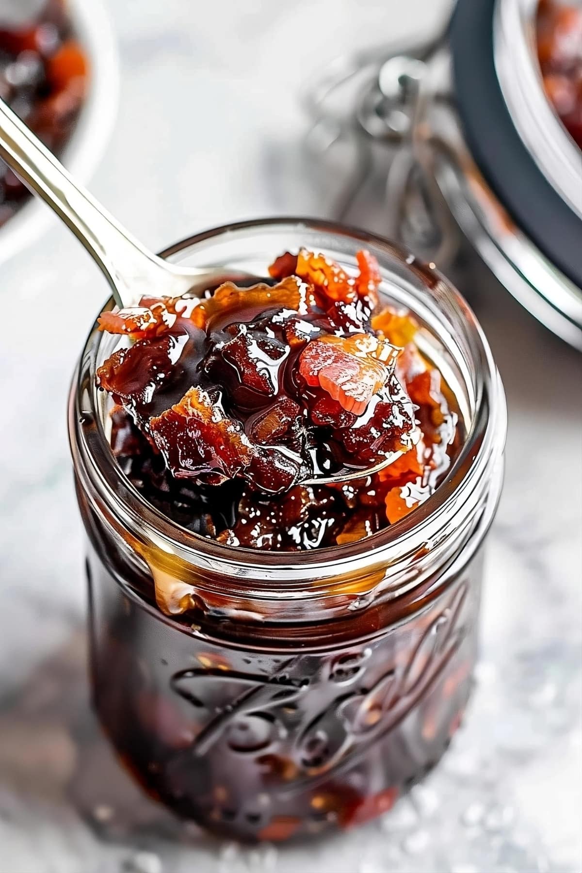 Bourbon bacon jam in a mason jar with a spoon scooping some from the top
