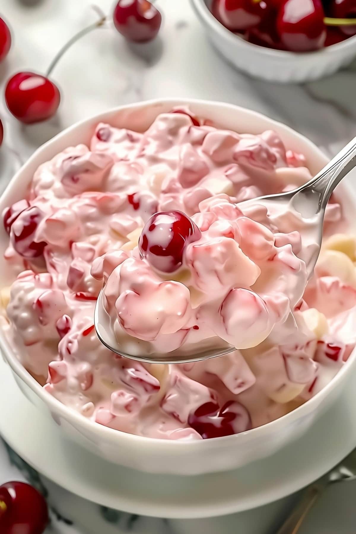 Spoonful of better than sex fruit salad with cherries in a creamy dressing.