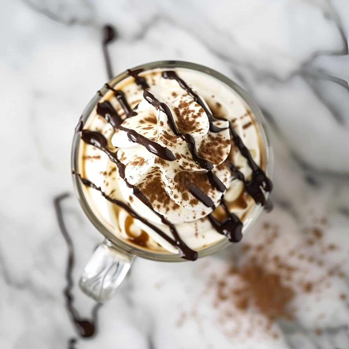 Top View Bailey's Hot Chocolate in a Glass Mug with Whipped Cream, Chocolate Syrup, and Cocoa Powder