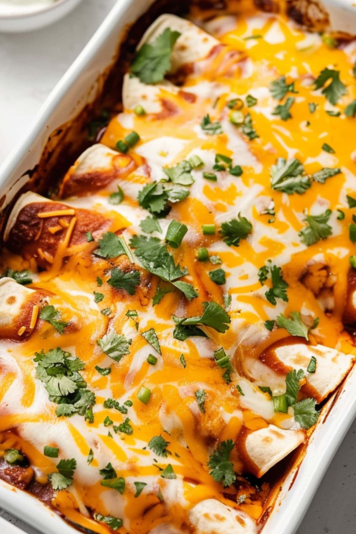 Beef enchiladas in a baking dish garnished with parsley on top.