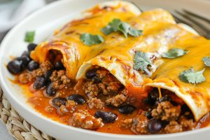 Three servings of beef enchiladas in a plate.