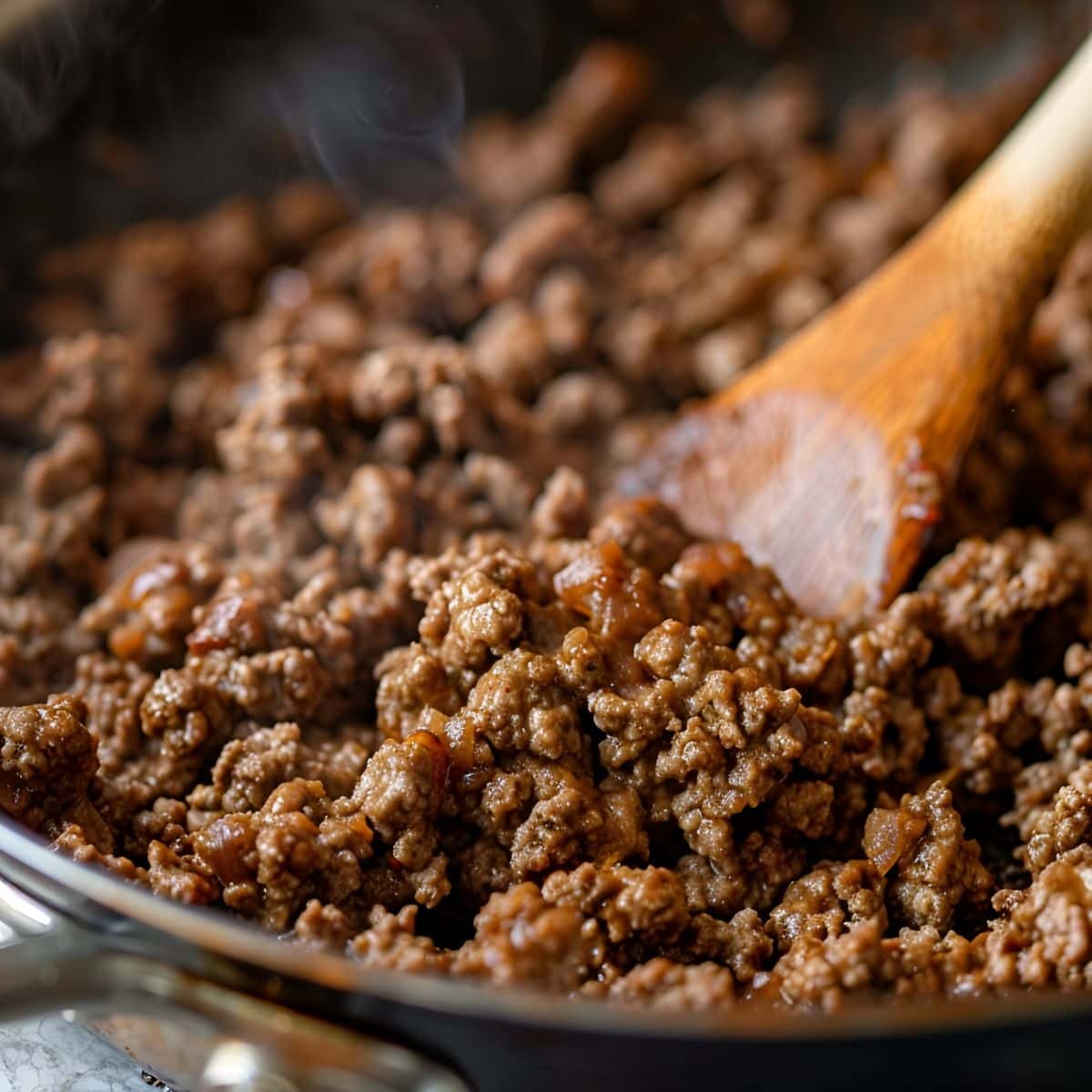 Close Up of Cooked Ground Beef in a Skillet with a Wooden Spoon