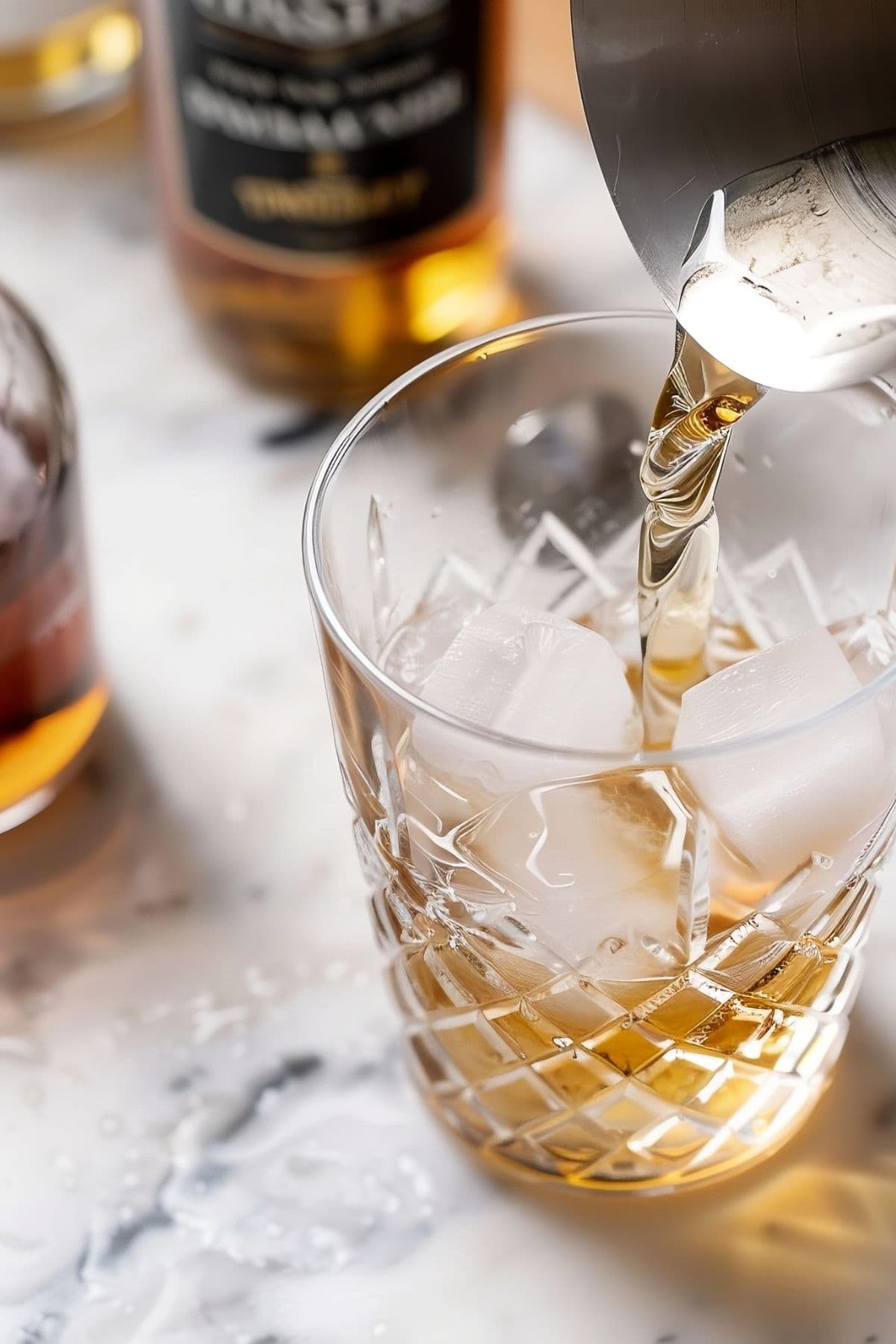 Pouring a Whiskey, Vermouth, and Cherry Liqueur Mixture into a Glass with Ice