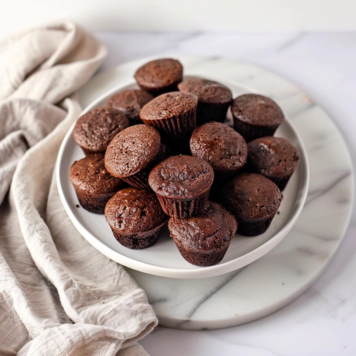 A bunch of brownie bites piled in a plate on a white marble counter top