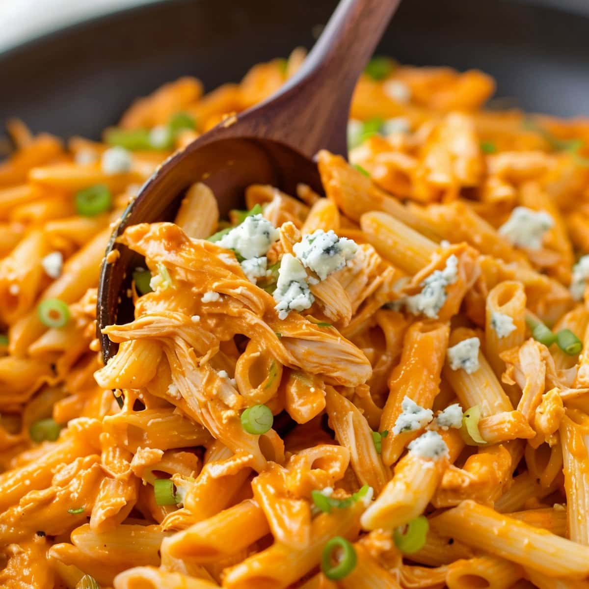 Creamy buffalo-flavored chicken penne pasta with blue cheese and chopped green onions