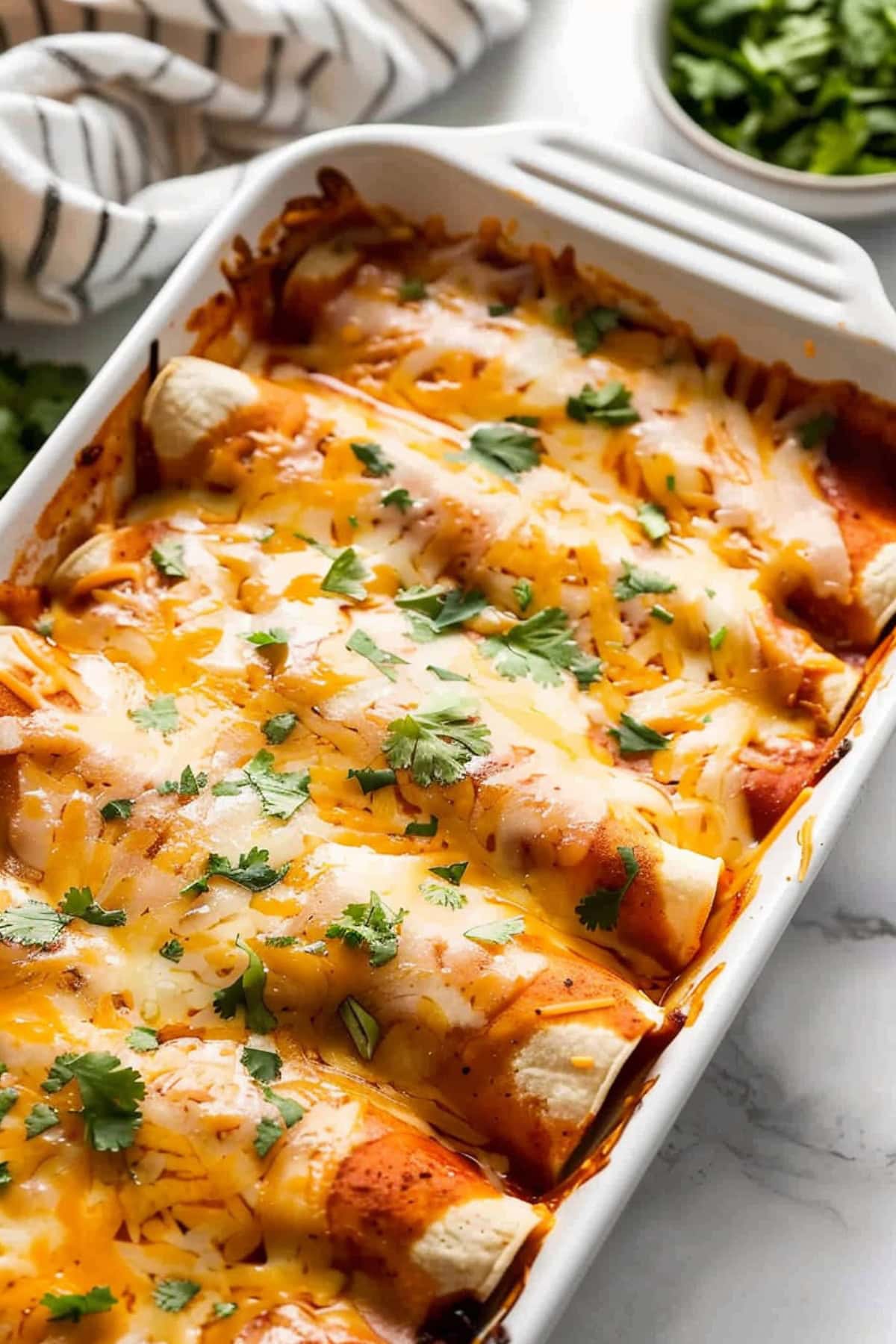 Chicken enchiladas topped with melted cheese and enchilada sauce.