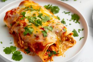 Serving of chicken enchiladas in plate.