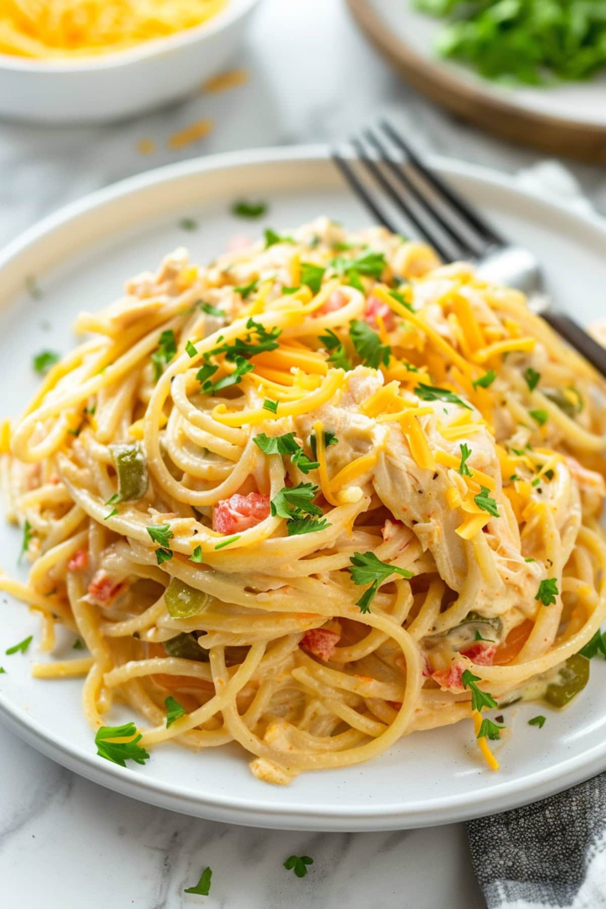 Cheesy chicken spaghetti casserole serving in plate with fork.