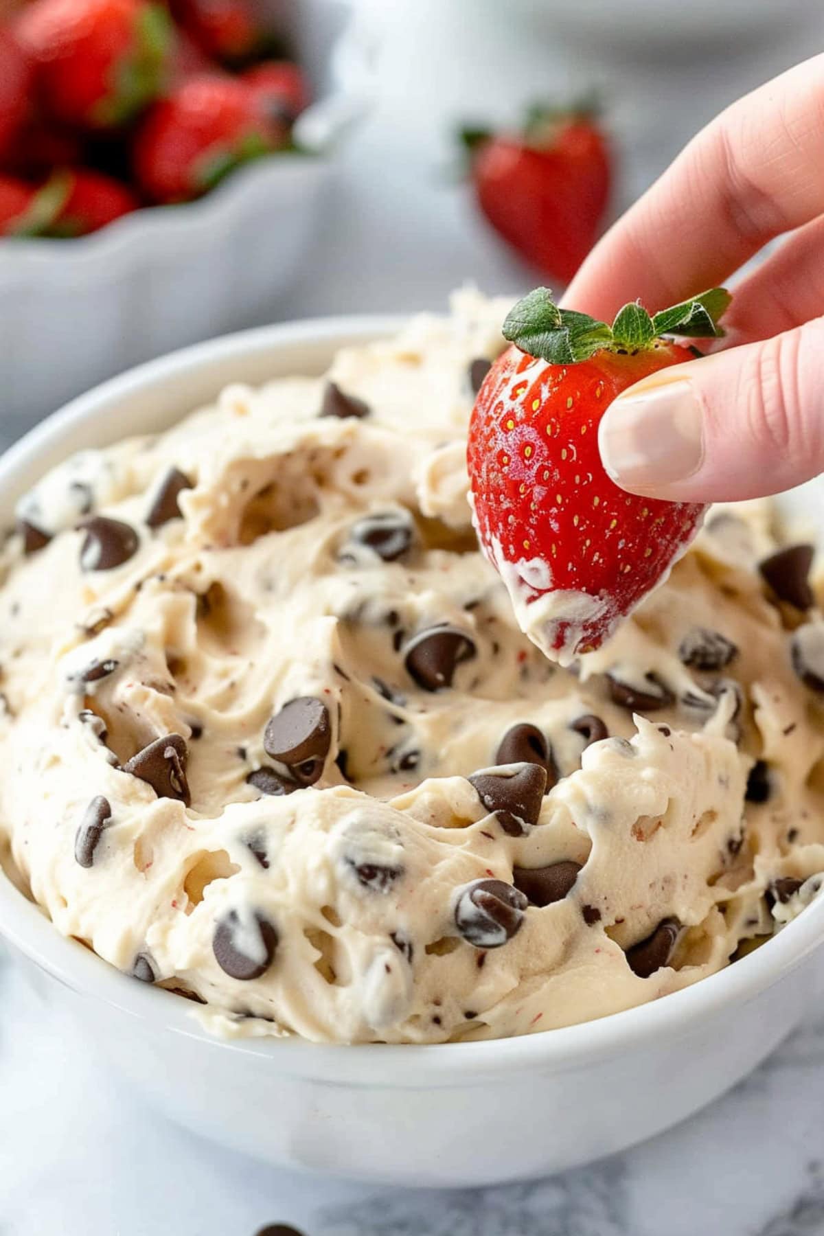 Whole strawberry dipped to a bowl of chocolate chip cookie dough dip