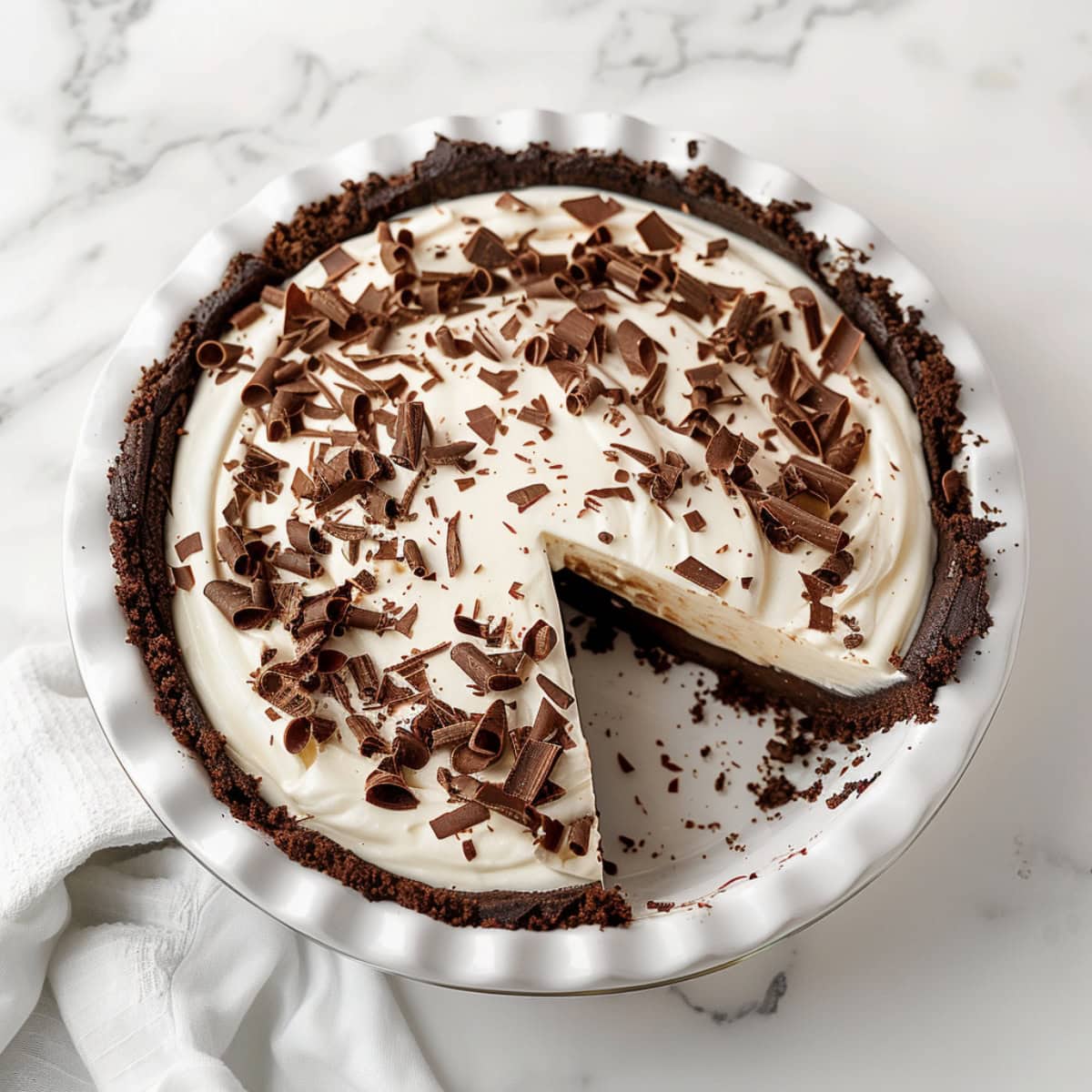 Top down view of a chocolate cream pie with a slice missing