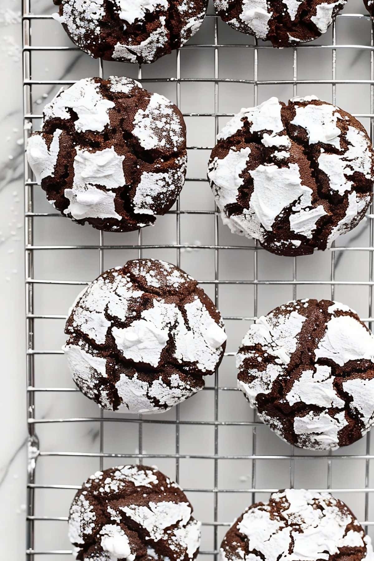Chocolate Crinkle Cookies Cooling on a Wire Rack Over a White Marble Table