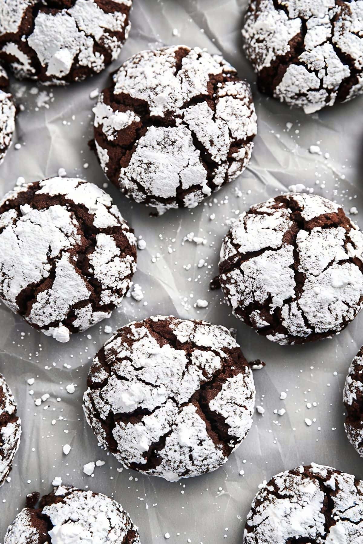 Close Top View Chocolate Crinkle Cookies with Powdered Sugar on Parchment Paper