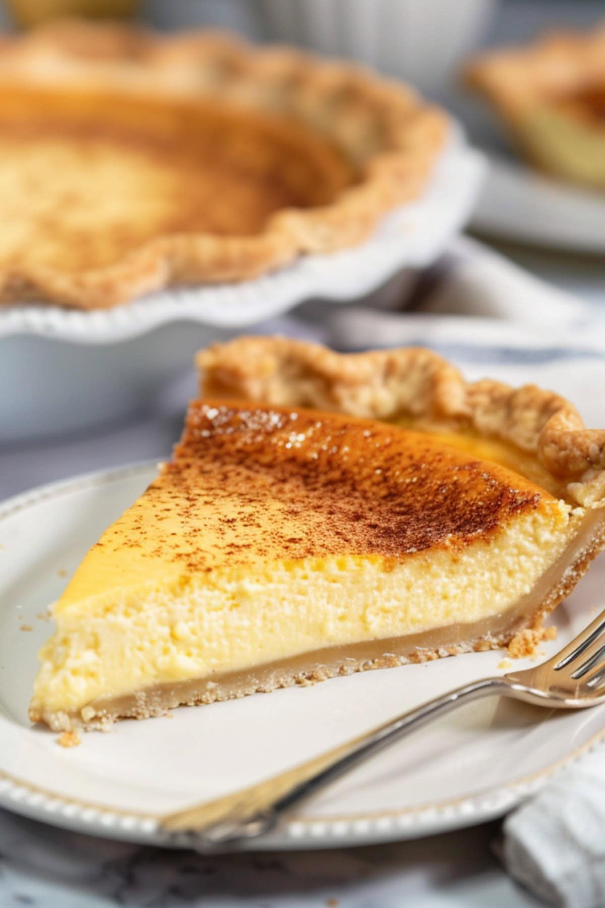 A slice of custard pie on a plate with a fork