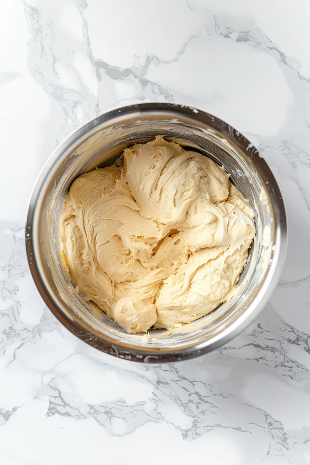 Creamy cookie dough in a metal mixing bowl.