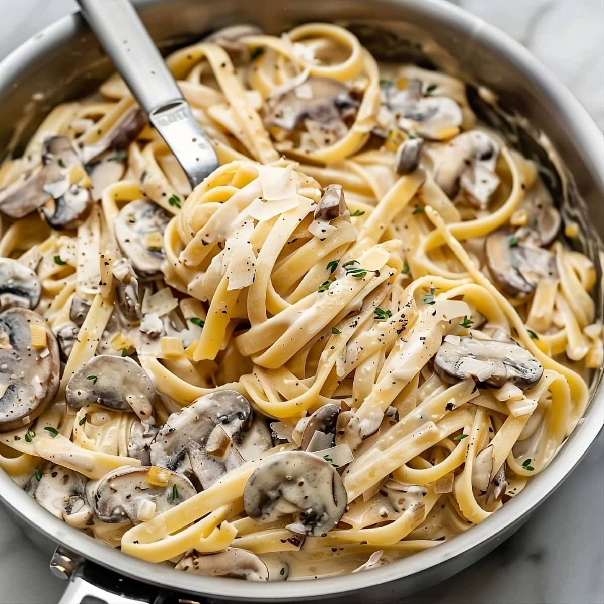 Mushroom pasta in creamy sauce on a skillet pan.