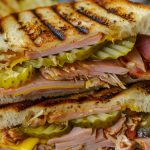 Two Halves Grilled Panini Cuban Sandwich with Ham, Pork,, Pickles, and Mustard Stacked