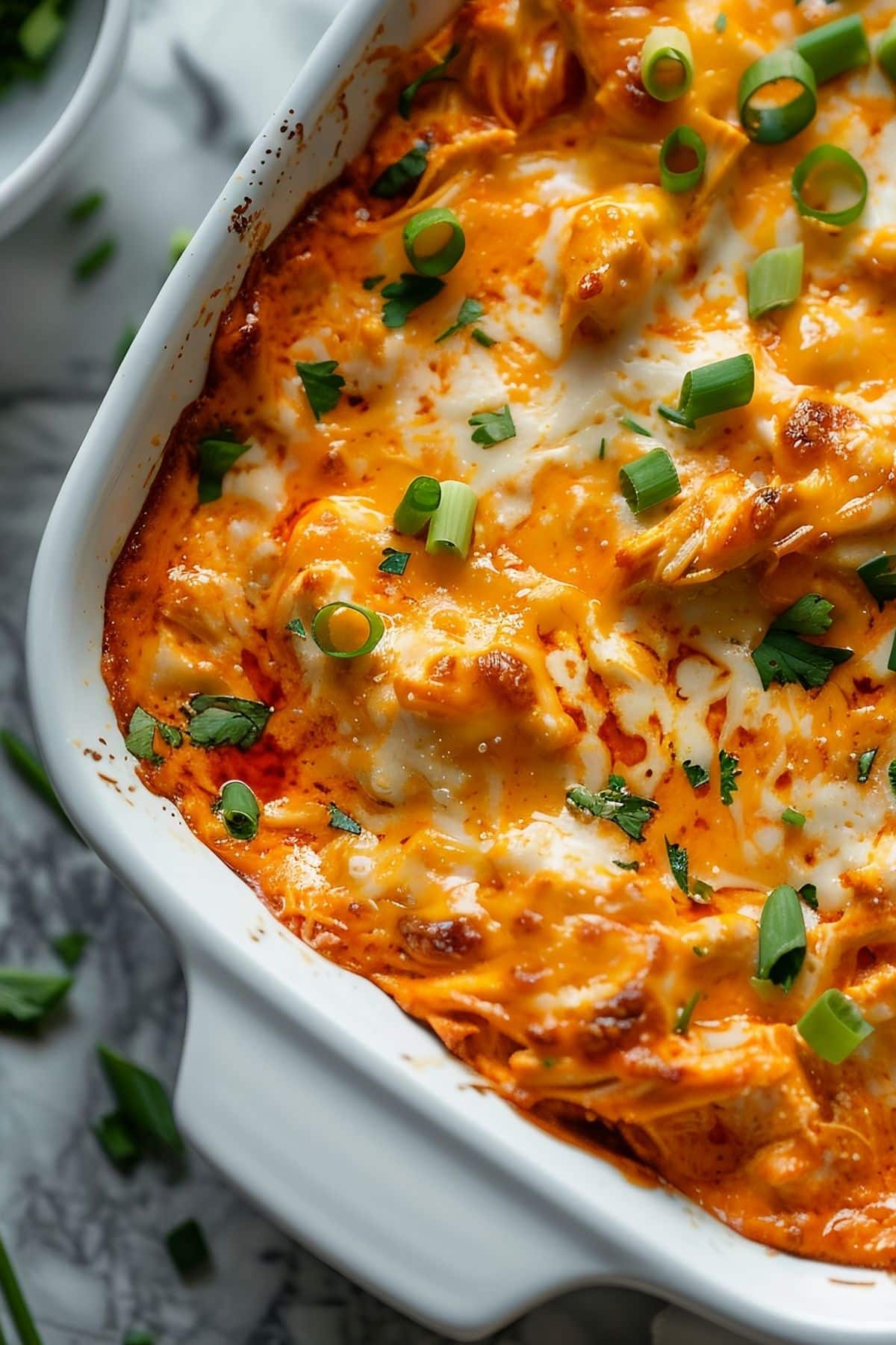 Close Up of Cheesy Frank's Buffalo Chicken Dip with Green Onions in a Casserole Dish