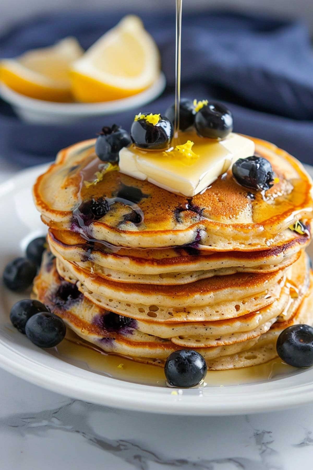 Fluffy homemade lemon blueberry pancakes topped with lemon zest and butter.