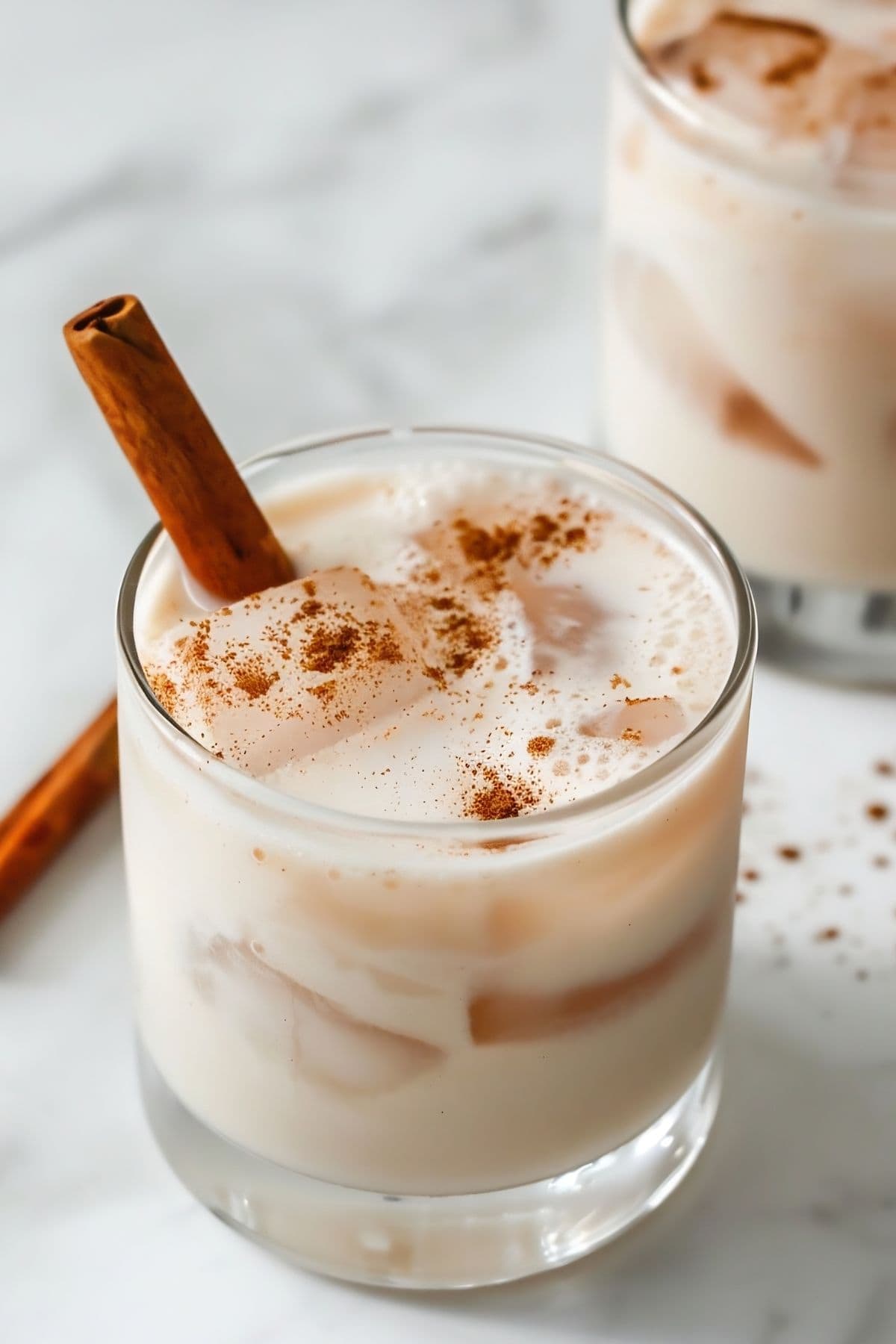 Creamy Mexican Horchata with Ice in a Glass with Cinnamon Dusting and a Cinnamon Stick