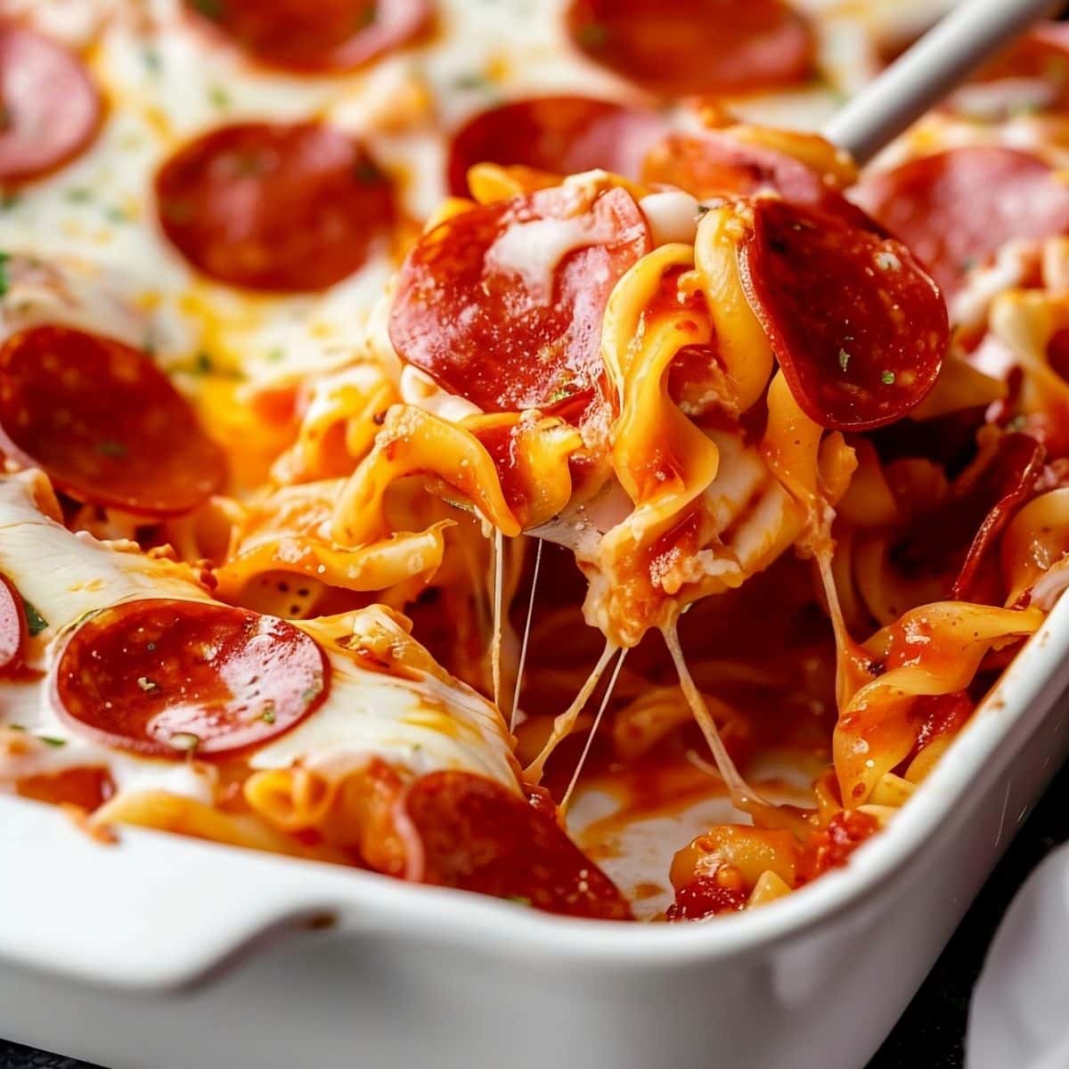 Scooping Out a Spoonful of Cheesy Gooey Pepperoni Pizza Casserole with Tomato Sauce, Lots of Cheese, Ground Beef, and Pepperonis