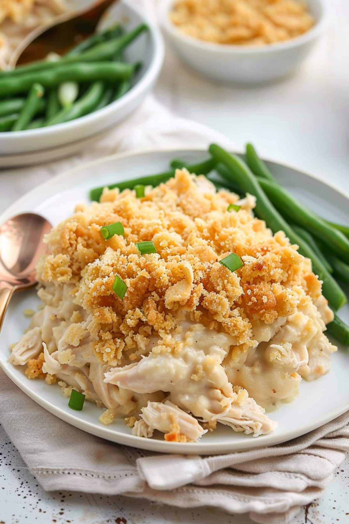 Serving of Ritz cracker chicken casserole in a white plate with green beans on the sides.