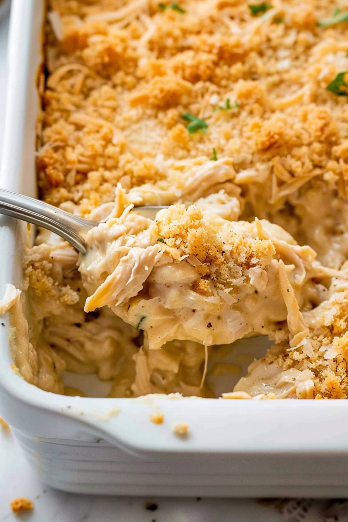 Spoonful of creamy chicken casserole in a baking dish.