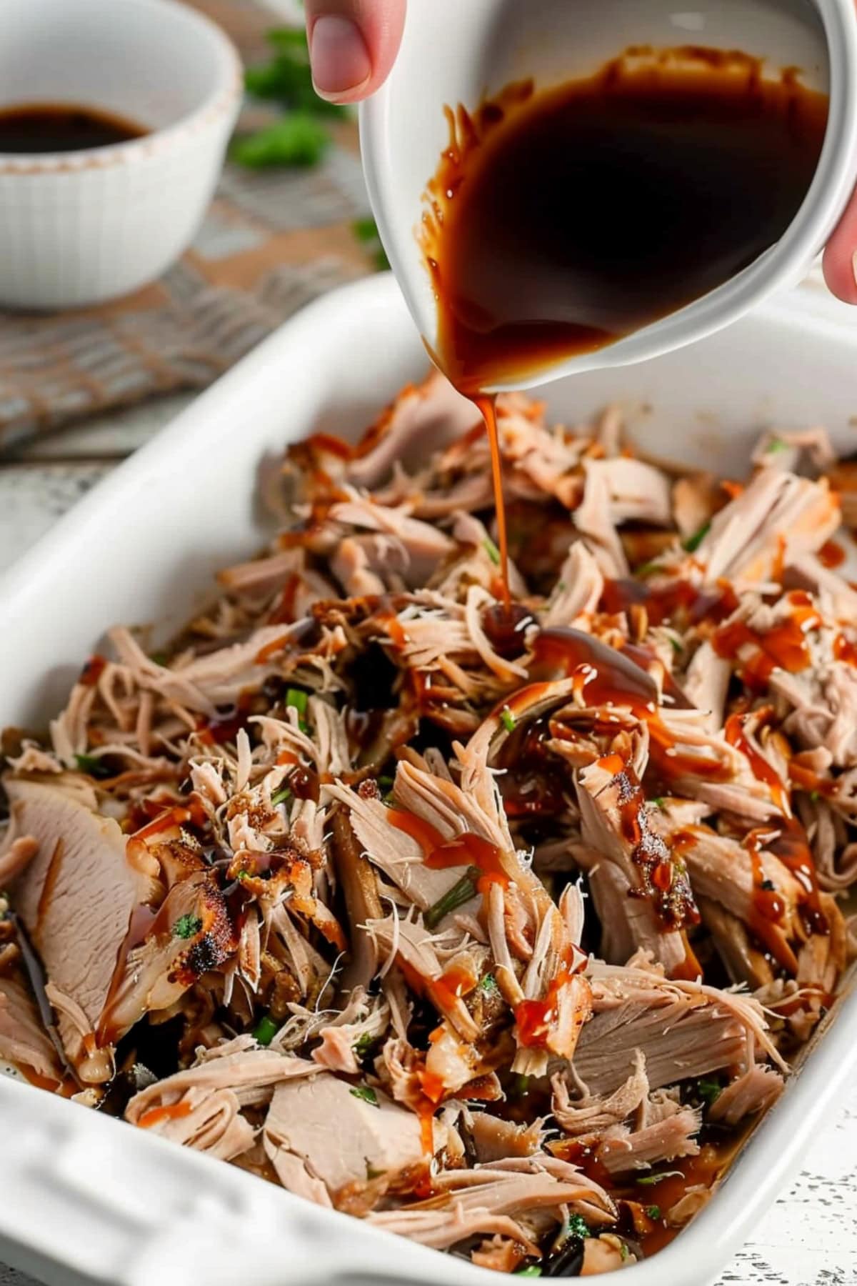 Shredded roast pork in a white dish poured with cooking sauce.