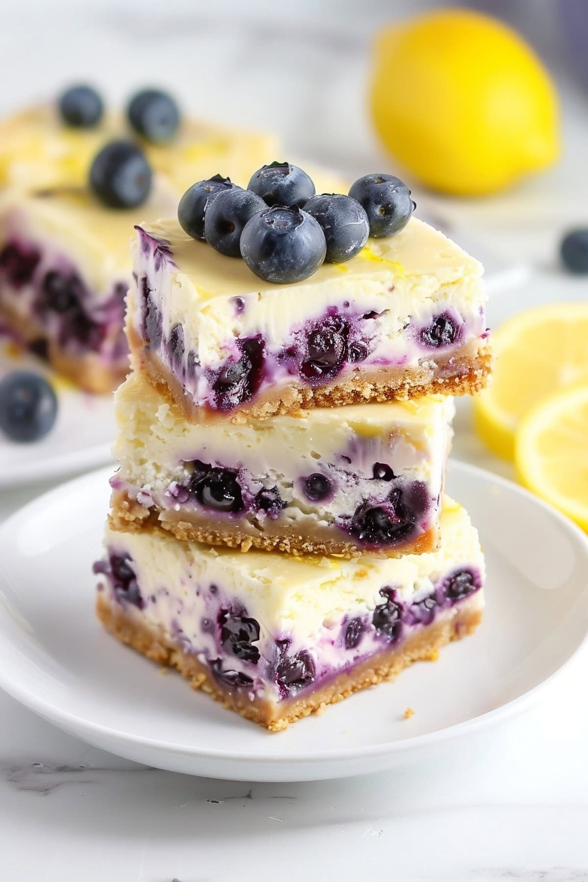 Close-up stack lemon blueberry cheesecake bars in a white plate.