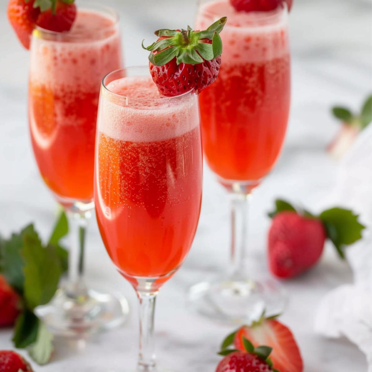 Three glasses of strawberry berlini garnished with fresh strawberries.