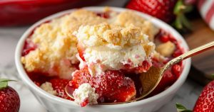 Strawberry Cheesecake Dump Cake scooping out of a bowl, close up