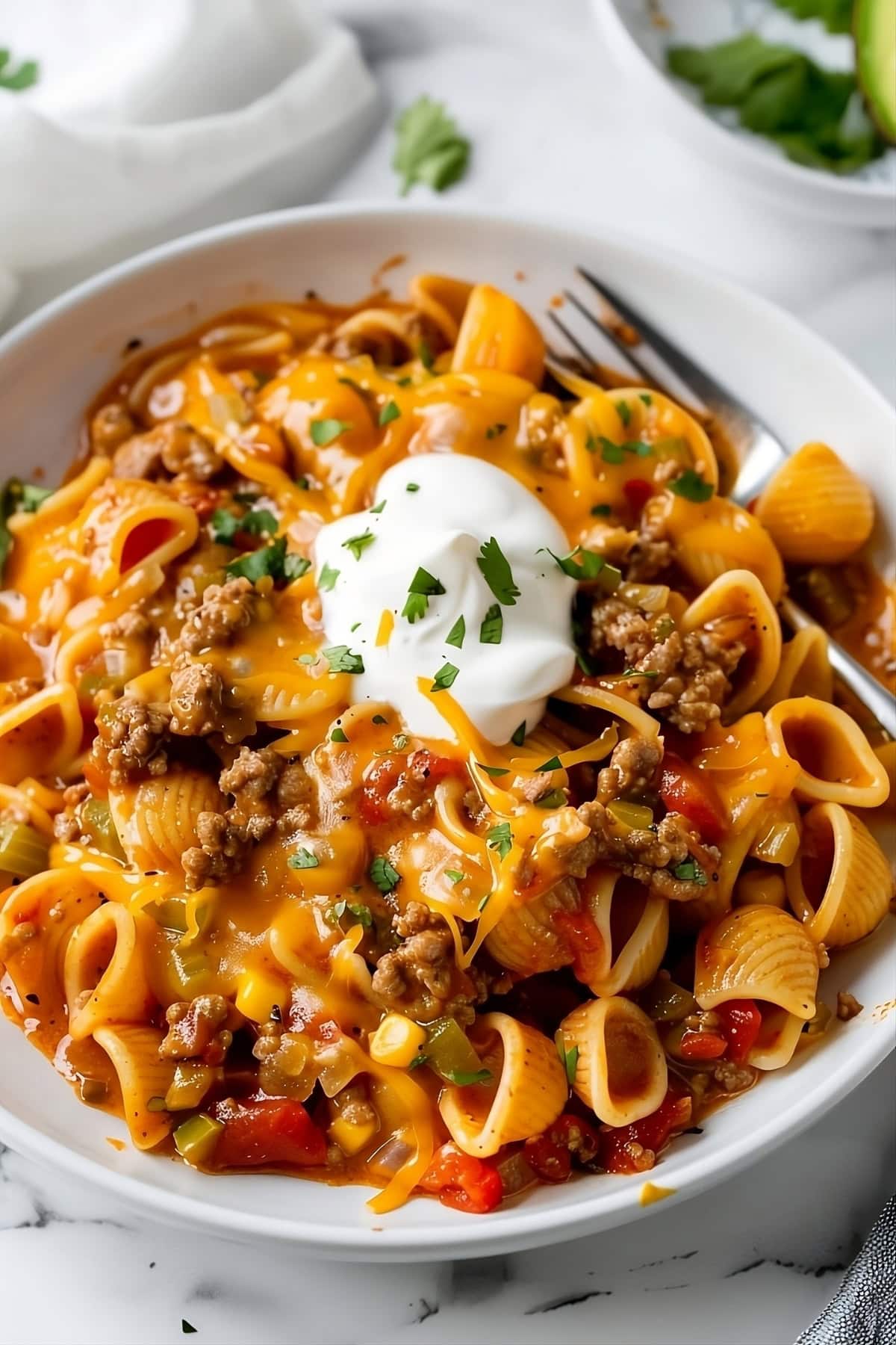 Serving of taco pasta with sour cream on top.