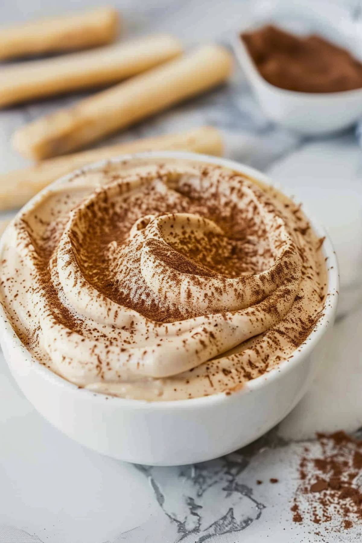Tiramisu dip in a white bowl dusted with cocoa on top.