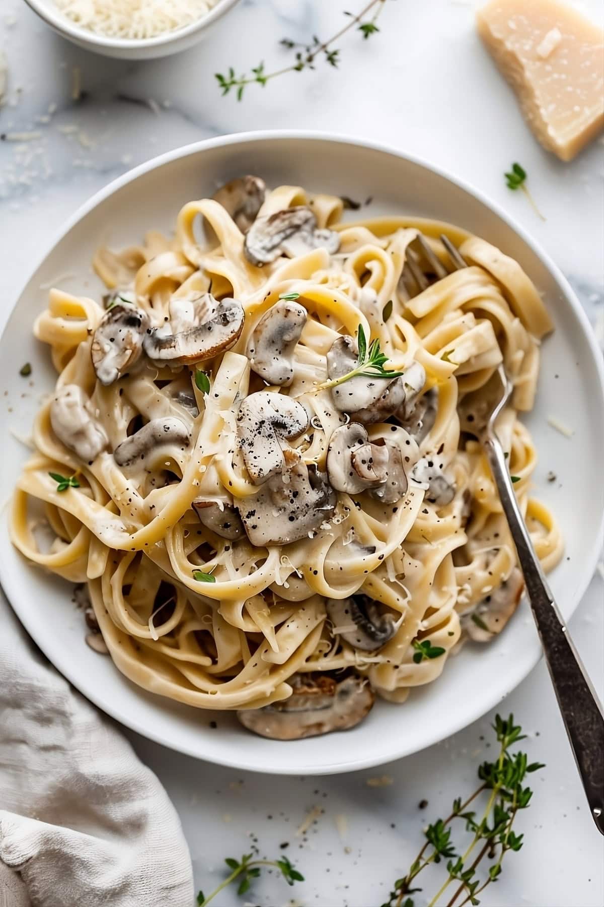 Serving of creamy mushroom pasta in a white plate with fork.