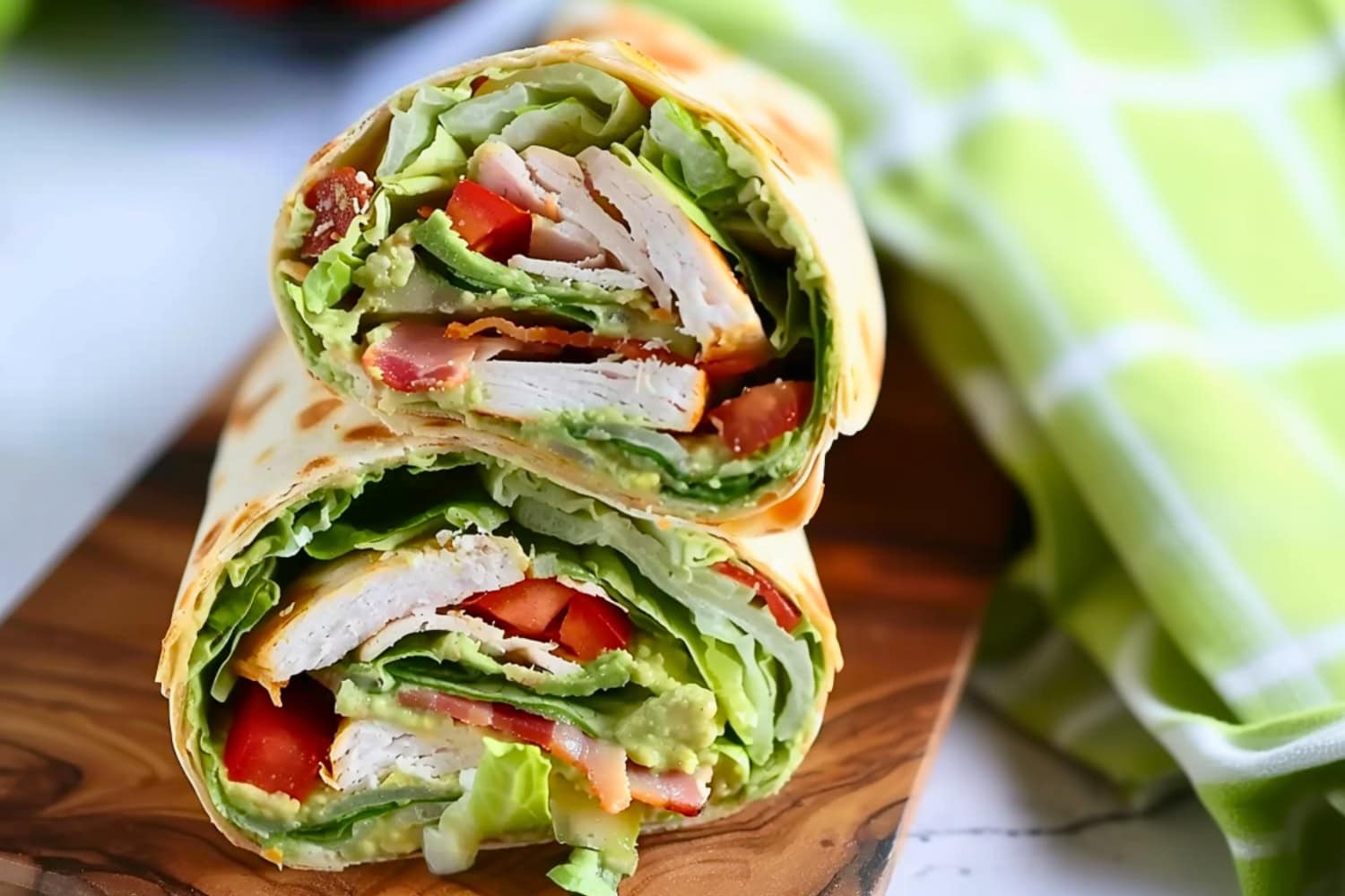 Sliced in half avocado turkey wrap in a wooden board.