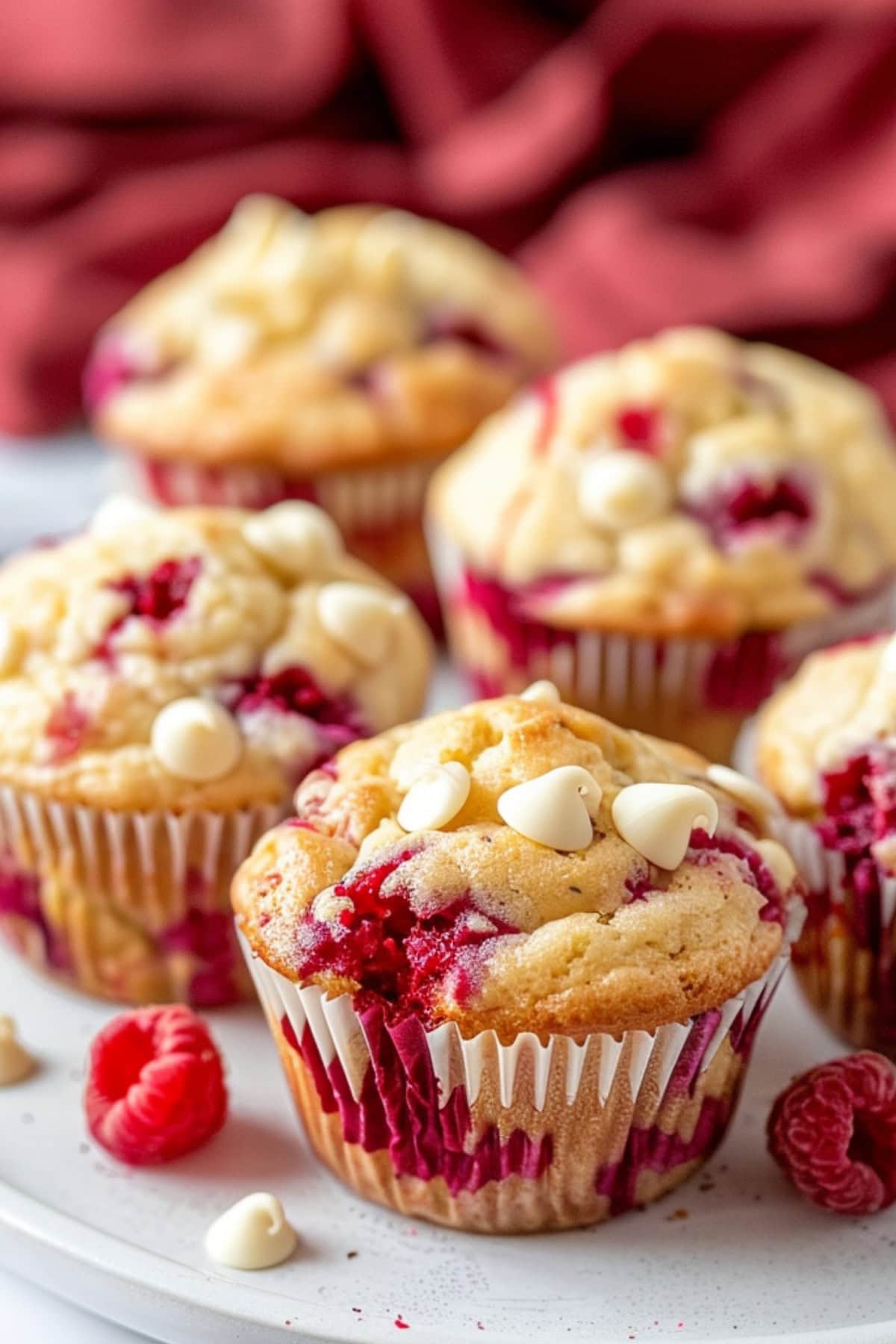 White chocolate raspberry muffins on a white plate.