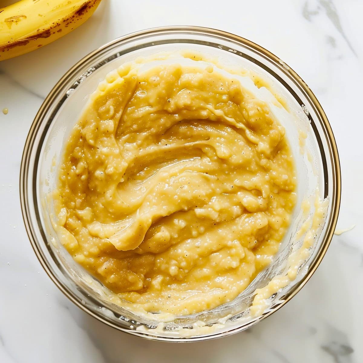 Banana Nut Muffin Batter in a Glass Bowl on a White Marble Table