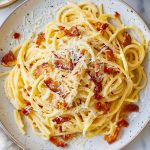 Close Up Top View of Plate of Pasta Carbonara with Bacon and Parmesan on a White Plate