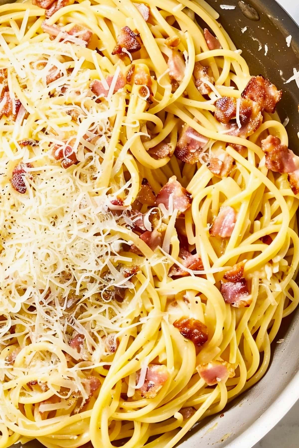 Close Up Top View Pasta Carbonara in a Pan with Bacon Pieces, Parmesan, and Noodles