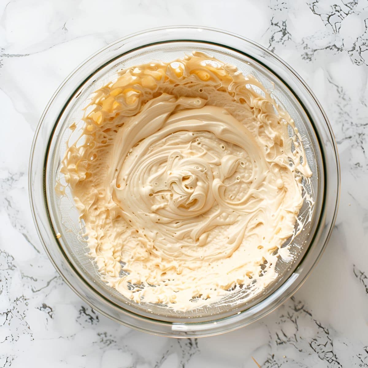 Top View of  7-Up Cake Batter in a Glass Bowl on a White Marble Table