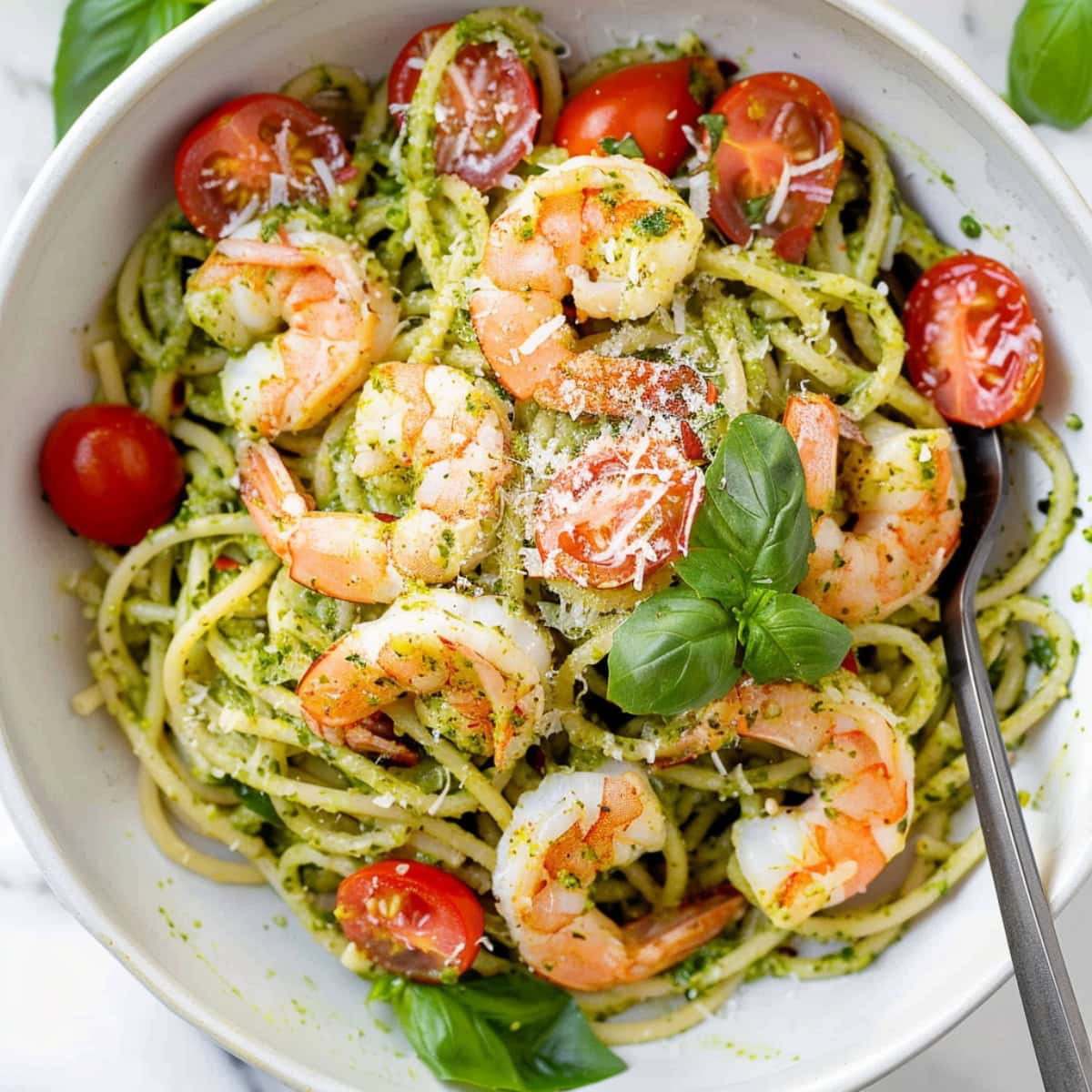 Vibrant pesto shrimp pasta, garnished with grated parmesan and basil.