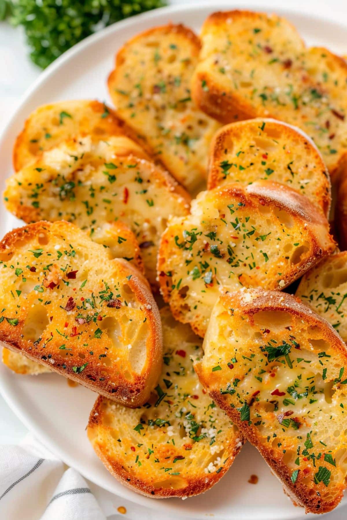 Bunch of baguette with garlic butter spread arranged in a white plate.