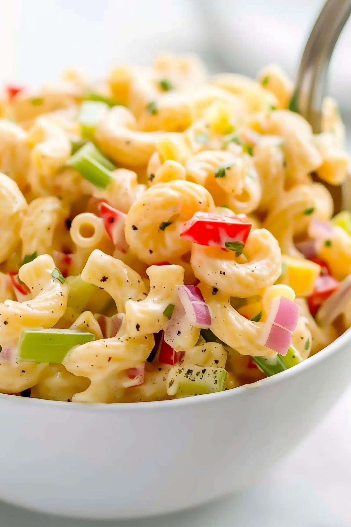 Close Up of Amish Macaroni Salad with Macaroni, Sauce, Red Onions, Celery, and Peppers in a White Bowl