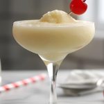 Close Side View of Banana Daiquiri in a Glass with a Maraschino Cherry Garnish