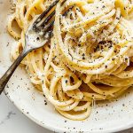 Close Up Top View of Cacio e Pepe with Sauce, Black Pepper, and Cheese with a Fork on a Plate