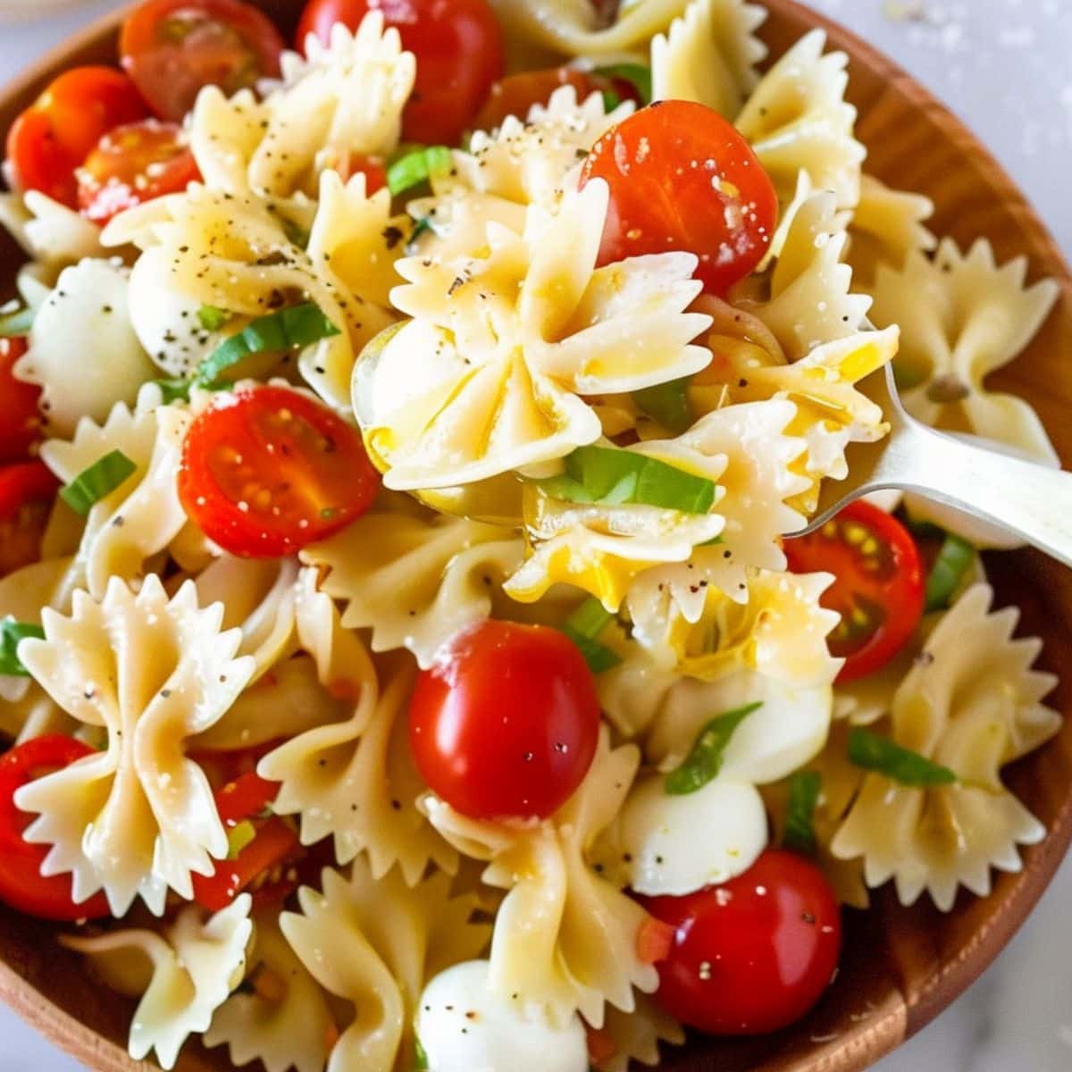 Caprese pasta salad in a wooden bowl. 
