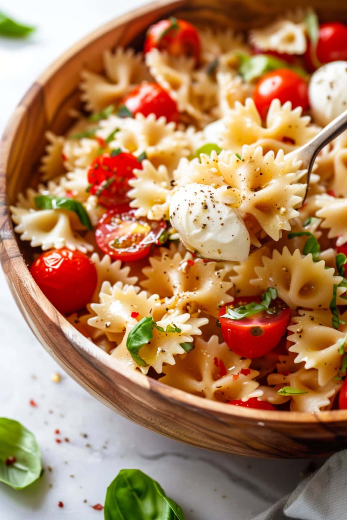 Caprese pasta salad in a wooden bowl. 