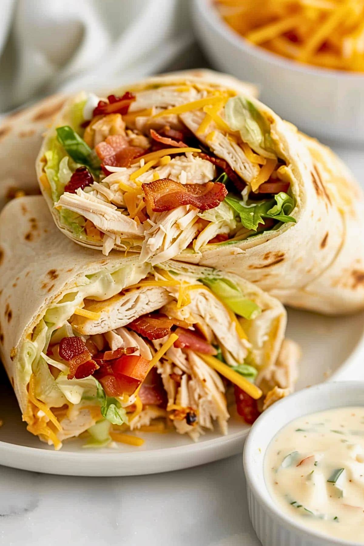 Shredded chicken with crumbled bacon, shredded lettuce, diced tomatoes, and cheese wrapped in tortilla.