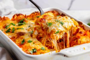 Ladle lifting a sliced portion of chicken enchilada casserole.