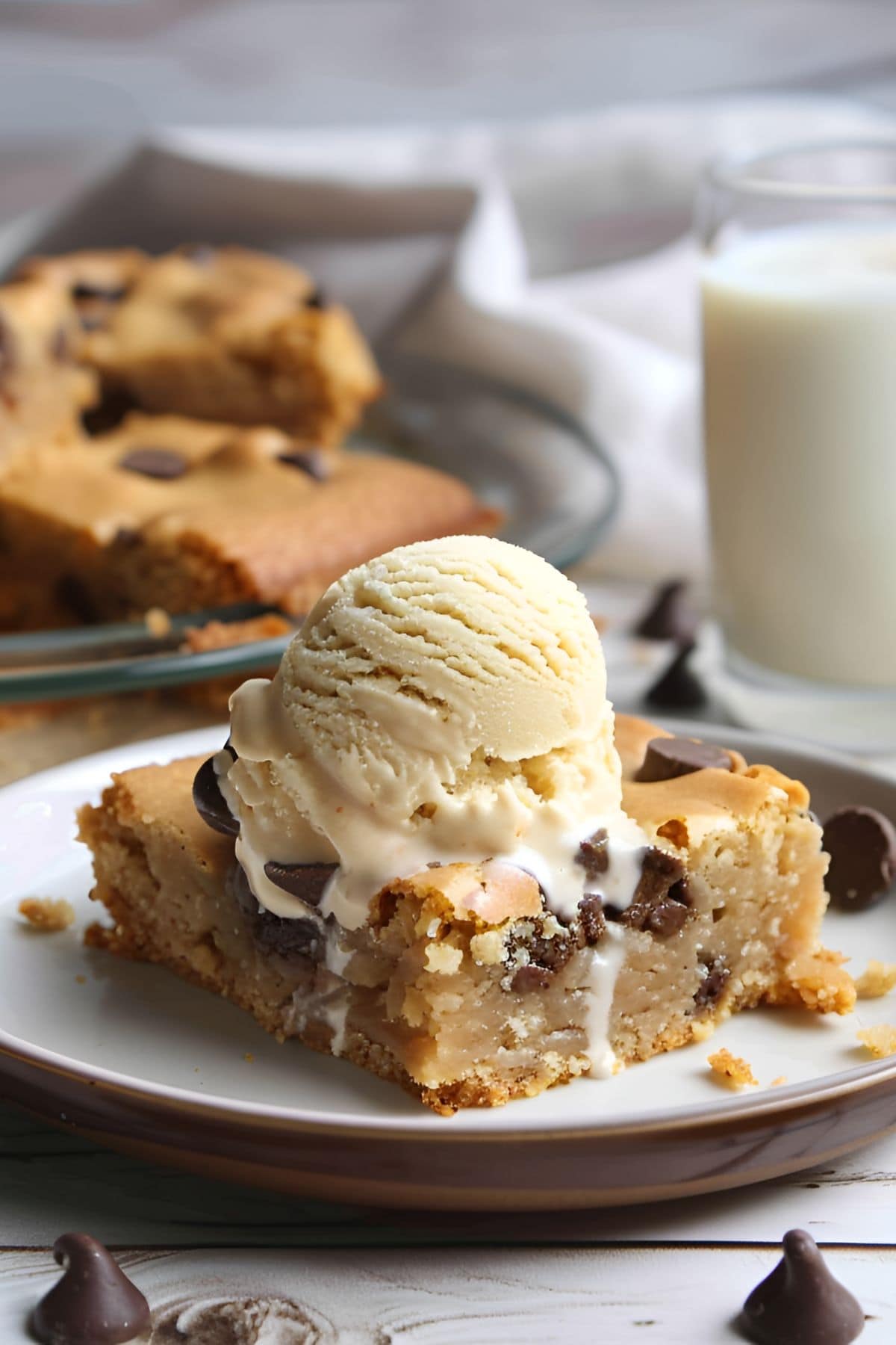 Chocolate Chip Blondie on a Plate with Vanilla Ice Cream and Milk in the Background