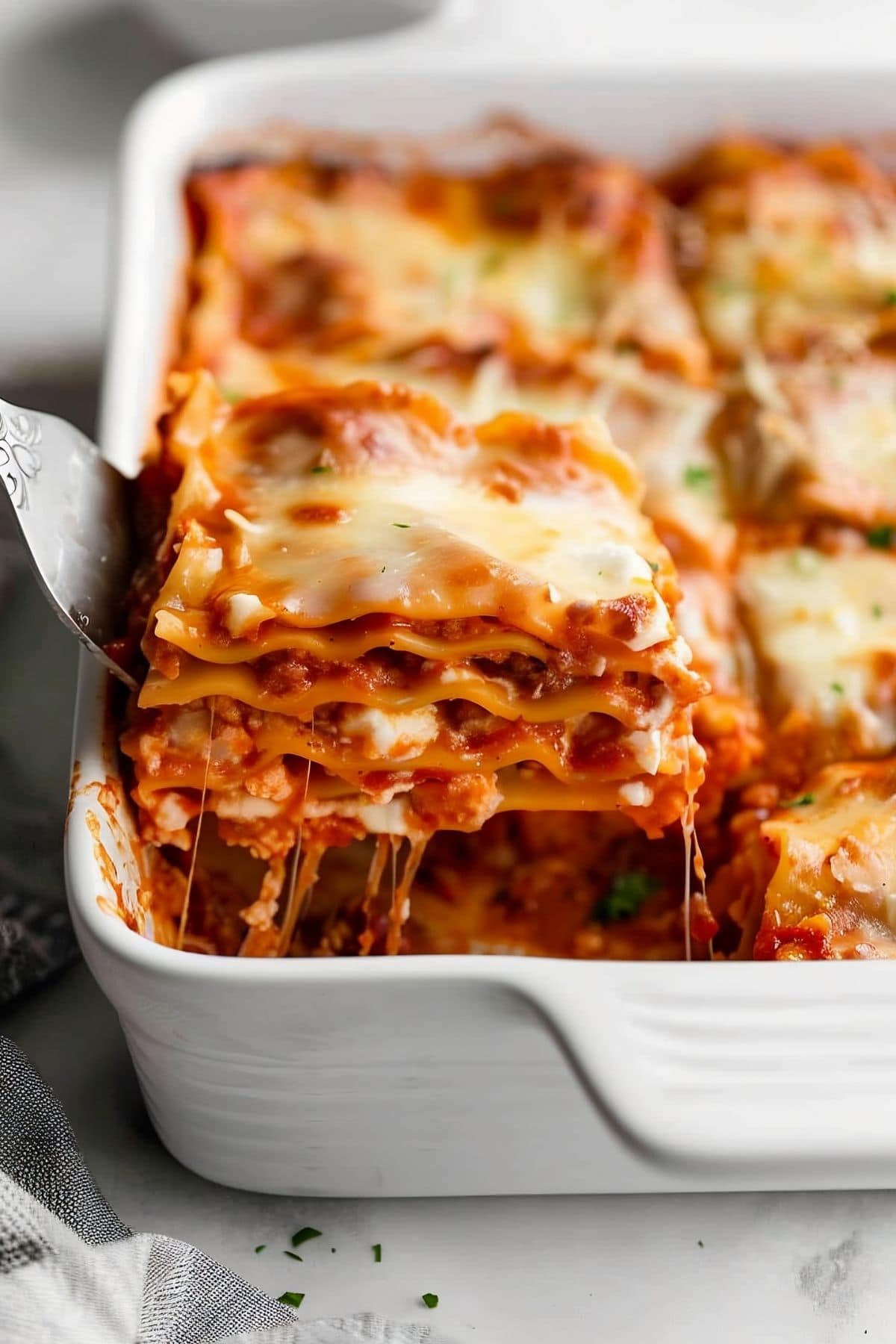 Spatula Pulling a Slice of Cheesy, Saucy Cottage Cheese Lasagna out of a Casserole Dish of Lasagna